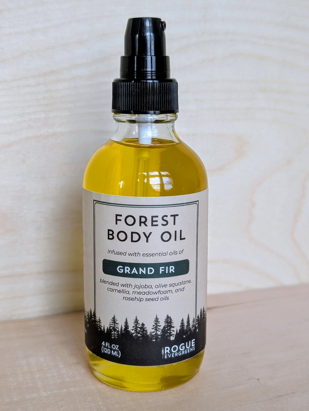 Bottle of Forest Body Oil with Grand Fir scent on a wooden surface