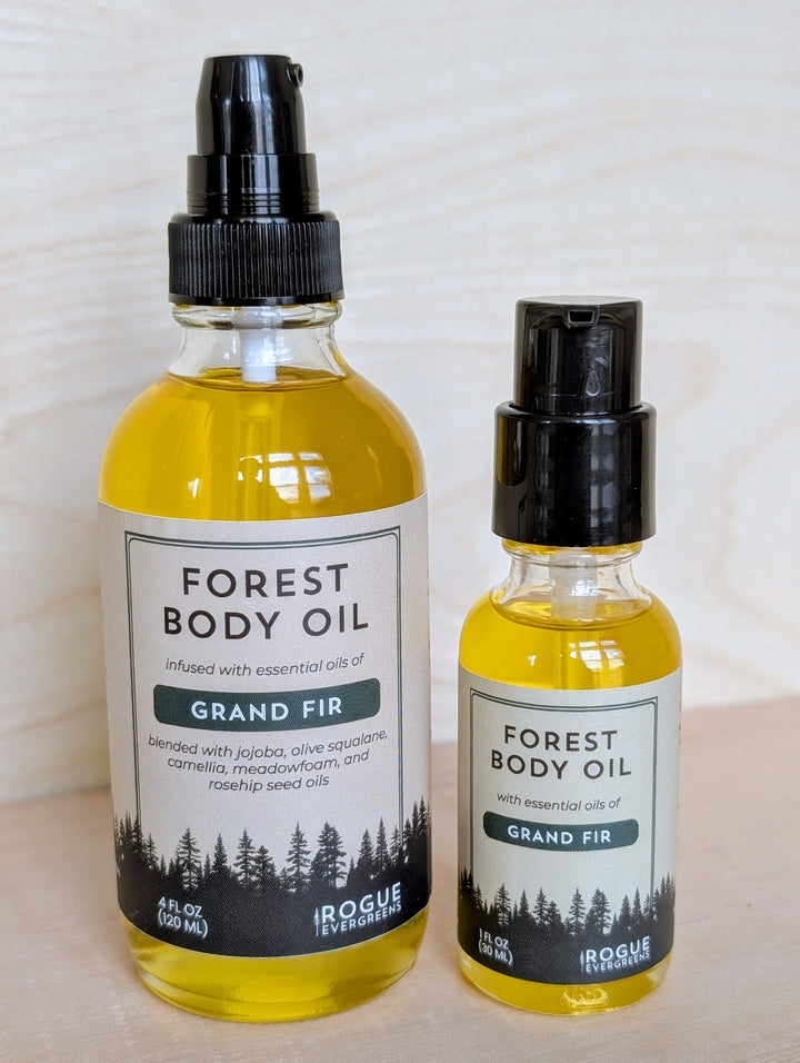 Two bottles of Forest Body Oil with Grand Fir scent on a light wooden surface.